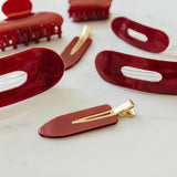 Desert Sol Garnet acrylic hair clip set with an oval lay flat claw clip, classic claw clip, petal claw clip and snap clips in deep red on white marble