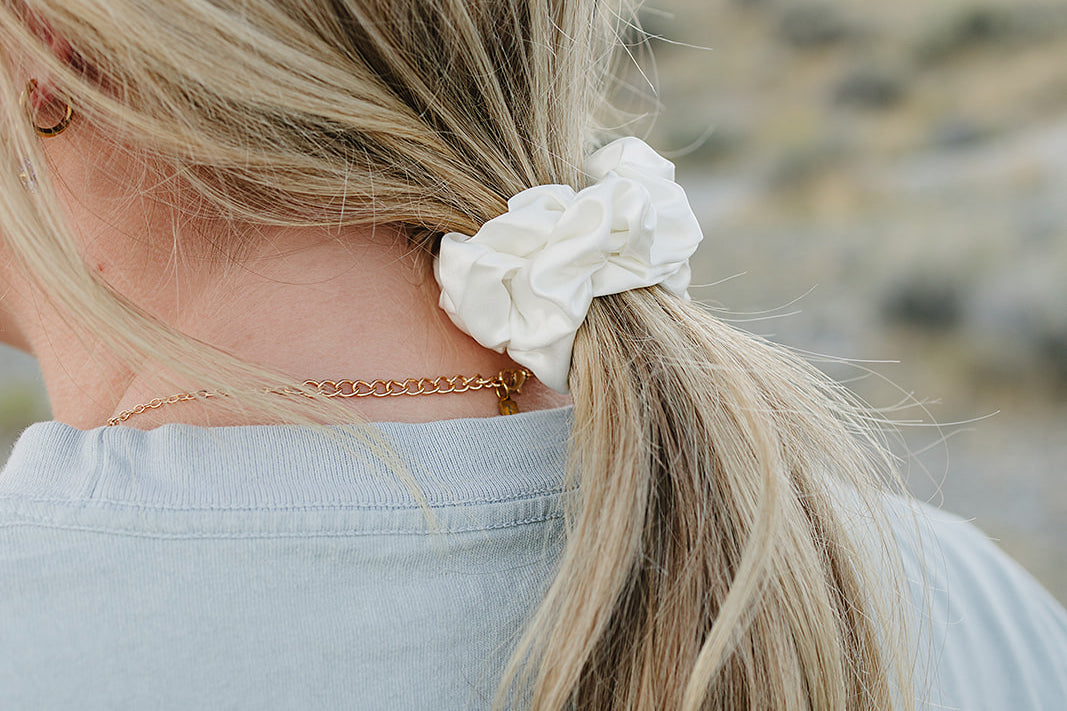 Low ponytail tied with the Desert Sol Mulberry Silk Scrunchie in Ivory