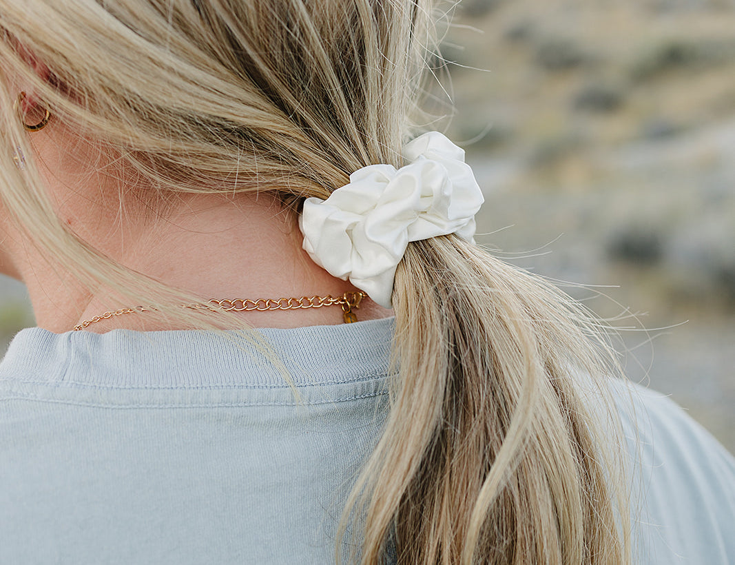 Low ponytail tied with the Desert Sol Mulberry Silk Scrunchie in Ivory