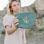 Model holding the Desert Sol Mono Cactus corduroy medium pouch in green