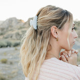 Model with a half up style held by the Desert Sol Classic Claw Clip in Moonstone, desert buttes behind her