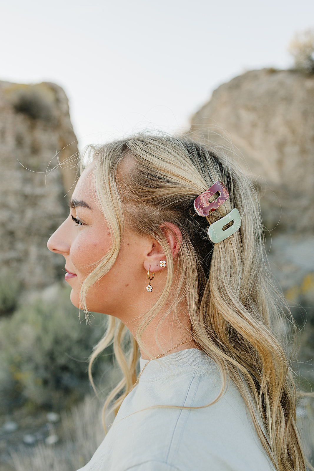 Model wearing a Mulberry Floral petal claw clip and a Soft Sage clip in a half up hairstyle