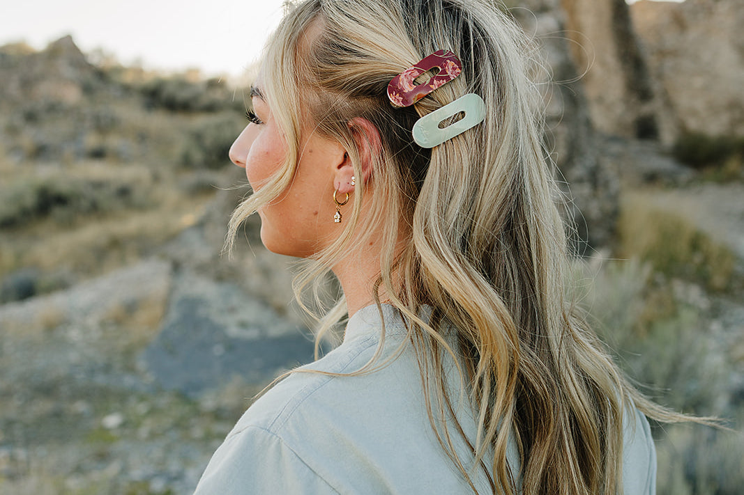 Model with a half up hairstyle held by a Soft Sage Oval Lay Flat Acrylic Claw Clip and a Mulberry Floral claw clip