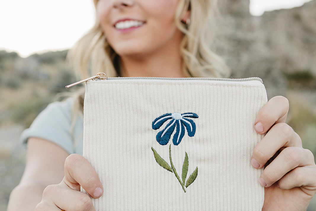 Model smiling and holding the Desert Sol Night Bloom corduroy flat pouch