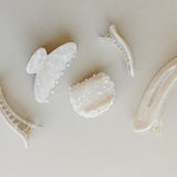 Desert Sol Pearl acrylic hair clip set with an oval lay flat claw clip, classic claw clip, petal claw clip and snap clips in a creamy white marble