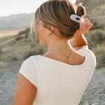 Model with a low bun held by the Desert Sol Oval Lay Flat Acrylic Claw Clip in Pearl