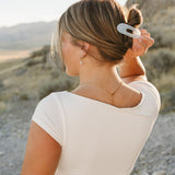Model with a low bun held by the Desert Sol Oval Lay Flat Acrylic Claw Clip in Pearl