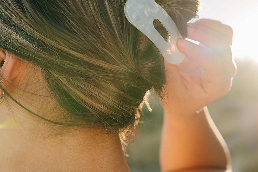 Close up of the Desert Sol Oval Lay Flat Acrylic Claw Clip in Pearl in a low bun at sunset