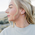 Model in profile wearing the Desert Sol Petal Hoop Earrings with a purple crystal flower