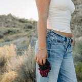 Model holding the Desert Sol Crystal Silk Scrunchie in Plum