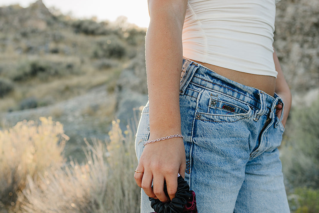 Model holding the Desert Sol Crystal Silk Scrunchie in Plum