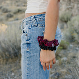 Desert Sol Crystal Silk Scrunchies in Plum and Black worn stacked on a wrist