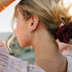 Model with a messy bun tied with the Desert Sol Mulberry Silk Scrunchie in Plum