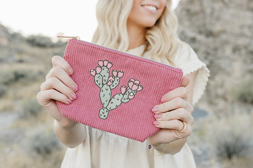 Model holding the Desert Sol Prickly Mauve Pear corduroy medium pouch in pink