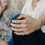 Model wearing the Desert Sol Solara pearl bracelet in gold and Canyon Marquise Ring, hand resting on her knee