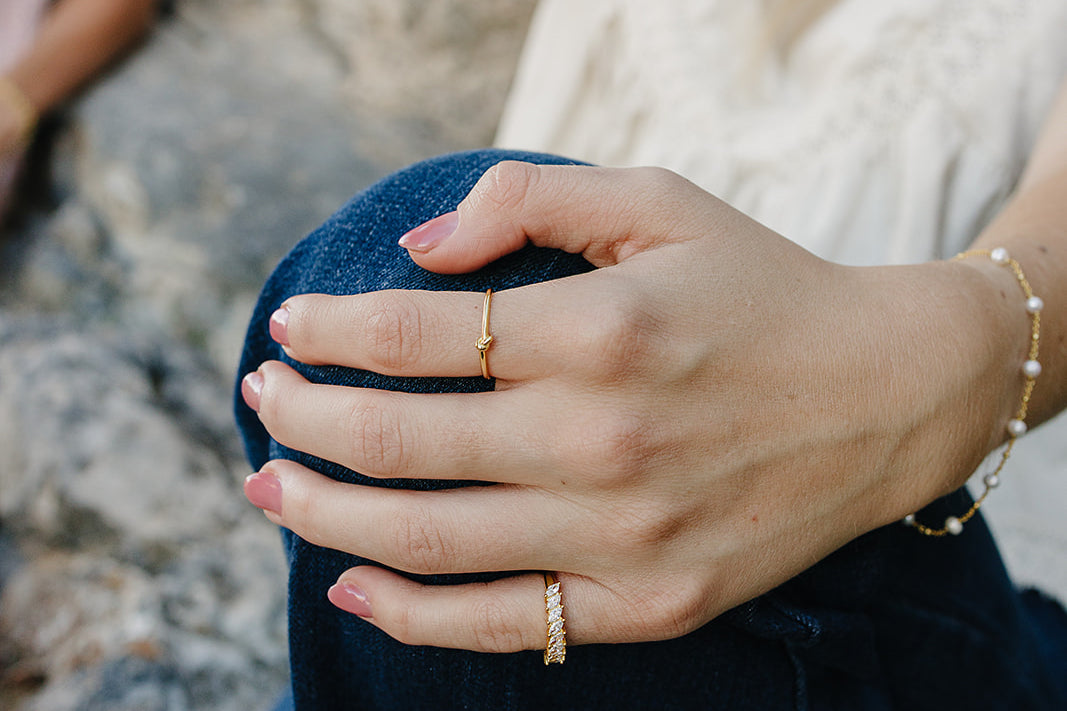 Model wearing the Desert Sol Solara pearl bracelet in gold and Canyon Marquise Ring, hand resting on her knee