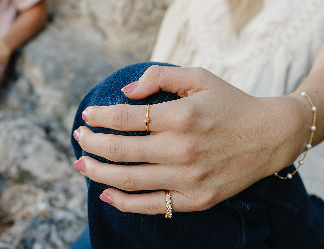Model wearing the Desert Sol Solara pearl bracelet in gold and Canyon Marquise Ring, hand resting on her knee
