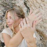 Model wearing the Desert Sol Solara pearl bracelet in gold with stacked gold rings