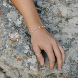 Desert Sol Solara pearl bracelet in silver and Canyon Marquise Ring on a hand resting on gray rock