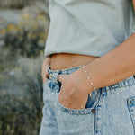 Desert Sol Solara pearl bracelet in silver on a hand in a jeans pocket