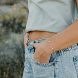 Desert Sol Solara pearl bracelet in silver on a hand in a jeans pocket