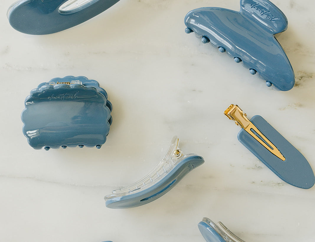 Desert Sol Storm Blue acrylic hair clip set with an oval lay flat claw clip, classic claw clip, petal claw clip and snap clips on white marble