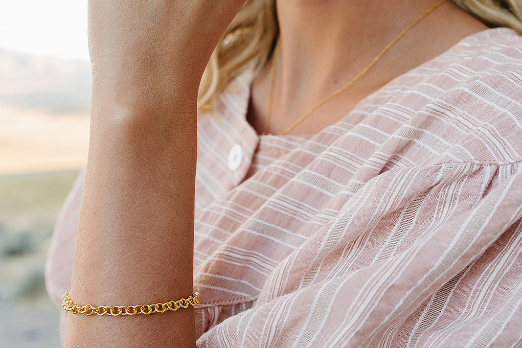 Model wearing the Desert Sol Sundown Chain Bracelet in gold and Petal Hoop Earrings in pink