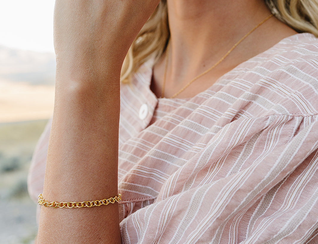 Model wearing the Desert Sol Sundown Chain Bracelet in gold and Petal Hoop Earrings in pink