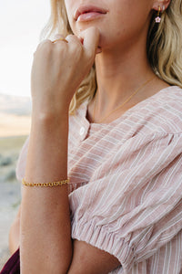 Model wearing the Desert Sol Sundown Chain Bracelet in gold and Petal Hoop Earrings in pink