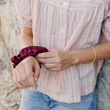 Model wearing the Desert Sol Sundown Chain Bracelet in gold with a plum Mulberry Silk Scrunchie on her wrist