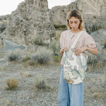 Model carrying the Desert Sol Utility Tote in Cactus Bloom in the desert