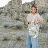 Model carrying the Desert Sol Utility Tote in Cactus Bloom in the desert