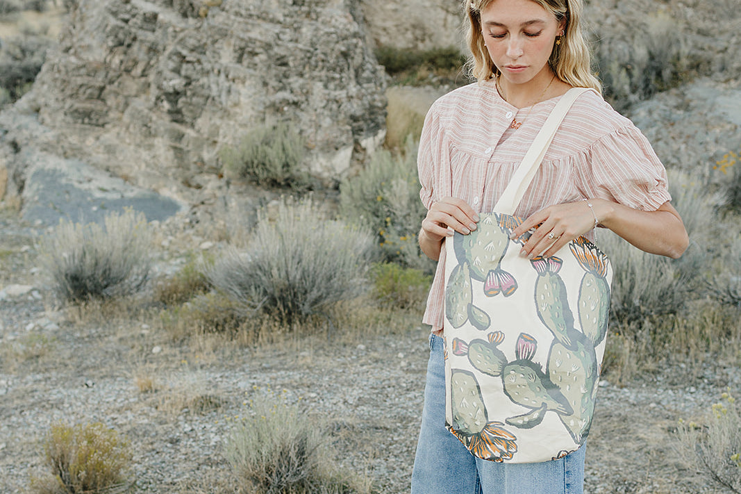 Model carrying the Desert Sol Utility Tote in Cactus Bloom in the desert