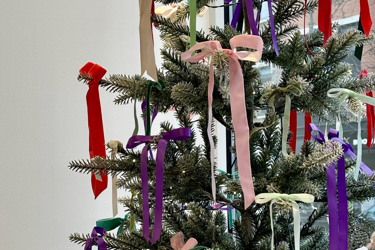 Flocked Christmas tree trimmed with velvet ribbon bows in pink, red, purple, green and cream