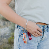 Desert Sol Wild Bloom Bracelet in silver with floral and garnet hair clips clipped to a jeans pocket