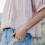 Desert Sol Wildflower Daisy Chain Bracelet in silver with Apricot Floral snap clips tucked in a jeans pocket