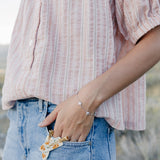 Desert Sol Wildflower Daisy Chain Bracelet in silver with Apricot Floral snap clips tucked in a jeans pocket
