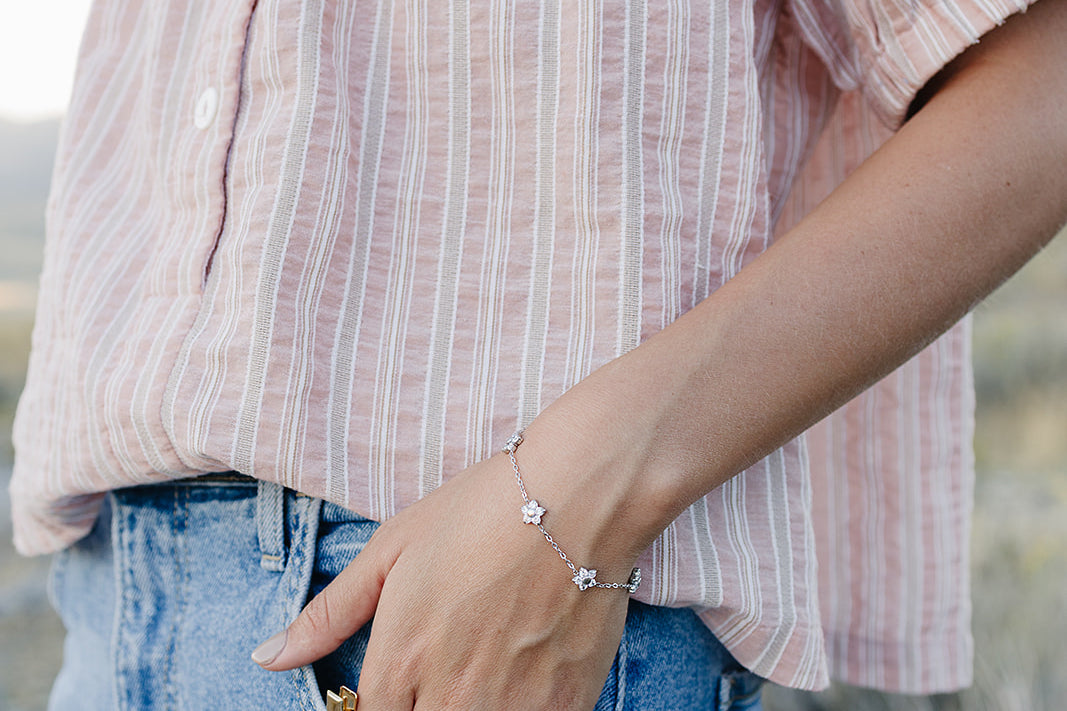 Desert Sol Wildflower Daisy Chain Bracelet in silver with Apricot Floral snap clips tucked in a jeans pocket