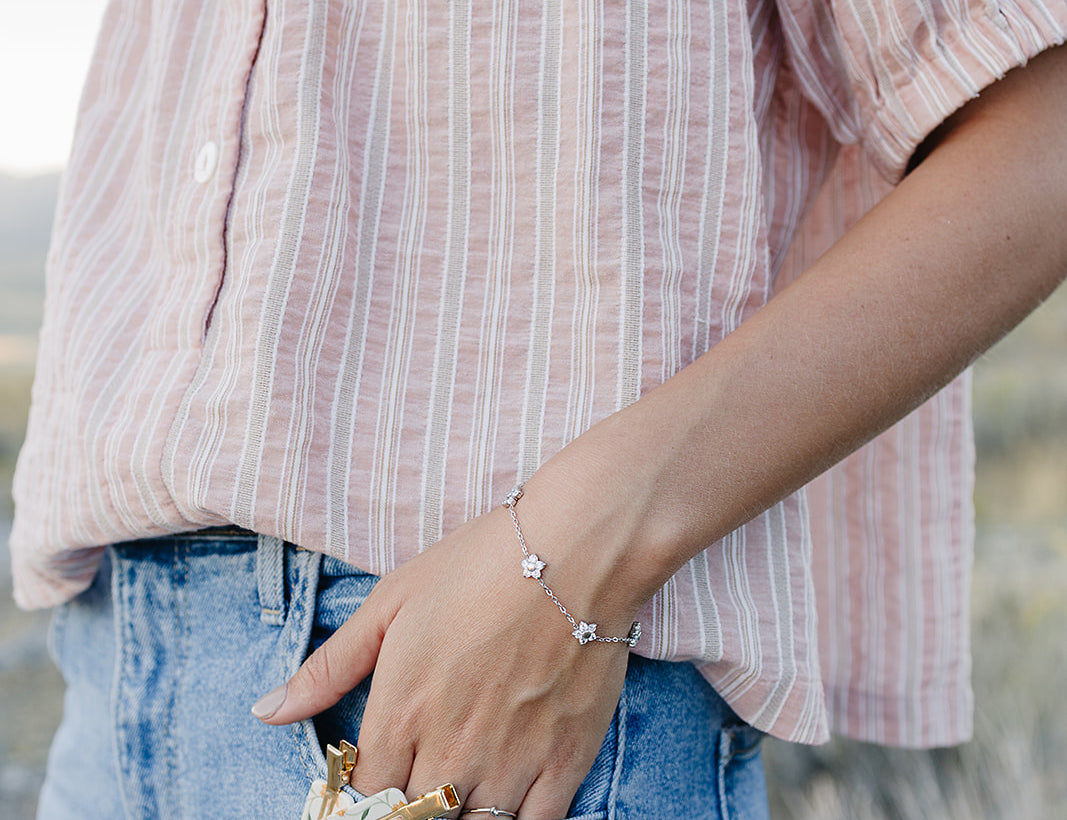 Desert Sol Wildflower Daisy Chain Bracelet in silver with Apricot Floral snap clips tucked in a jeans pocket