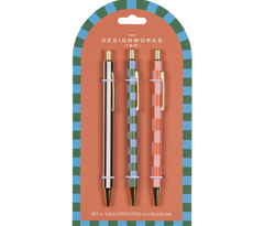 A Dopo Pen Set of 3, three patterned ballpoint pens, one gold, one green striped and one pink patterned, on a blue and green checkered backer card