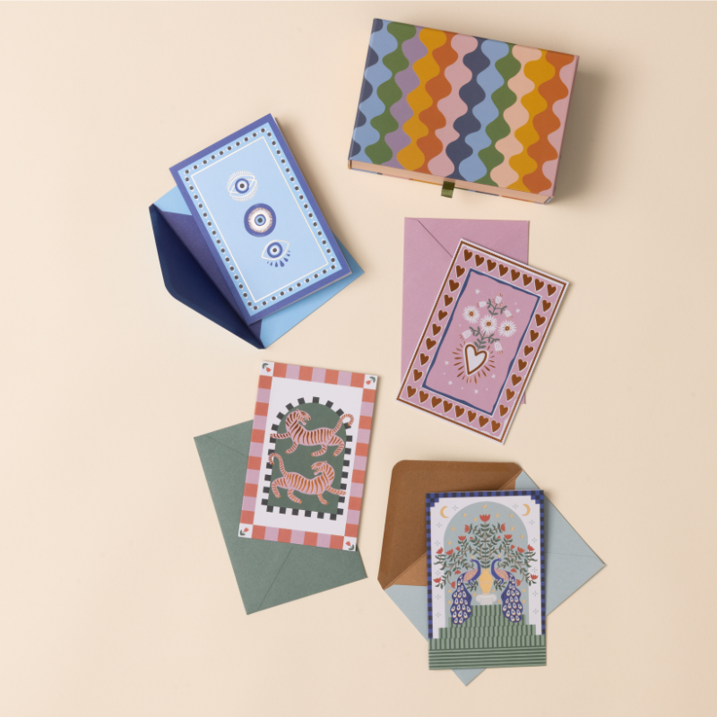 Designworks Notecards Set of 16, colorful patterned box with assorted floral and folk-art cards and envelopes fanned out