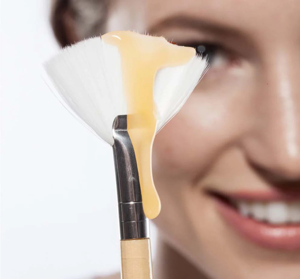Farmhouse Fresh Honey Heel Glaze dripping from a fan brush beside a smiling woman