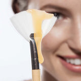 Farmhouse Fresh Honey Heel Glaze dripping from a fan brush beside a smiling woman
