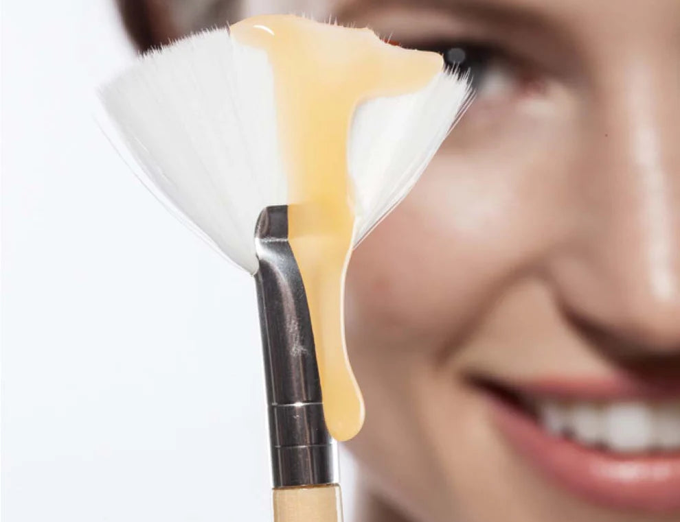 Farmhouse Fresh Honey Heel Glaze dripping from a fan brush beside a smiling woman