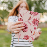 The Mulberry Floral Gesture hardcover notebook held out at arm's length, a blush cover with deep rose blooms.