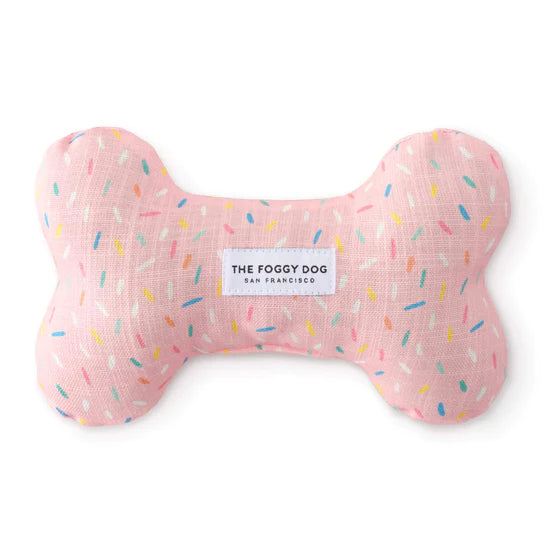 Foggy Dog Dog Squeaky Toy in Sprinkles, a pink plush bone with a colorful sprinkle print