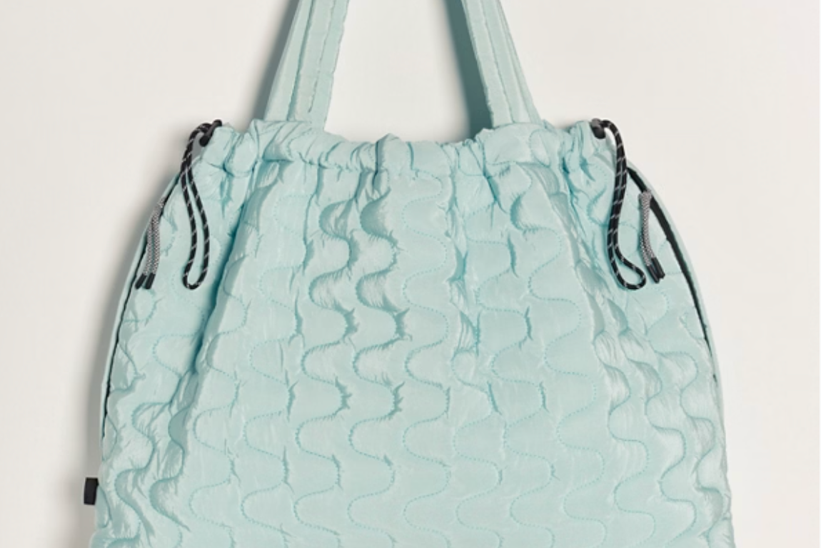 Free People Movement Cloud 9 quilted tote in pistachio, hanging by its long shoulder straps
