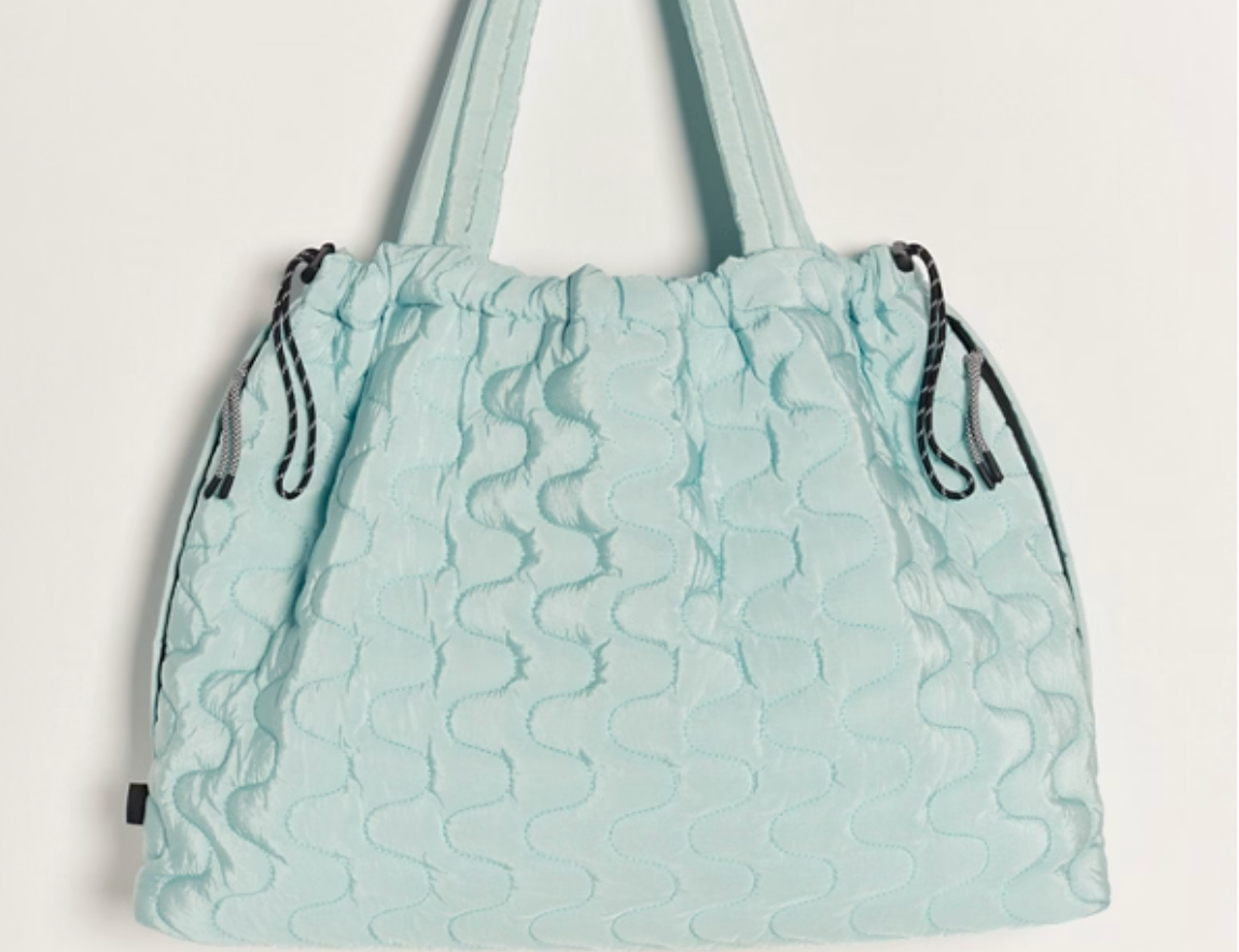 Free People Movement Cloud 9 quilted tote in pistachio, hanging by its long shoulder straps