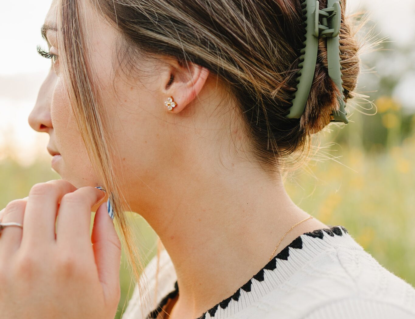 The Sagebrush Frenchie claw clip in soft green holding a low twist, worn with gold Petal stud earrings.