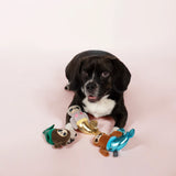 Black and white spaniel lying with the Fringe Studio Mersloth plush dog toys on a pink background